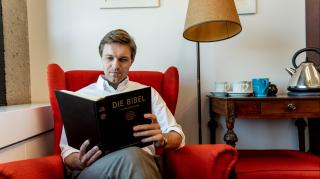 Photo of Florian Gassner reading a book in his office